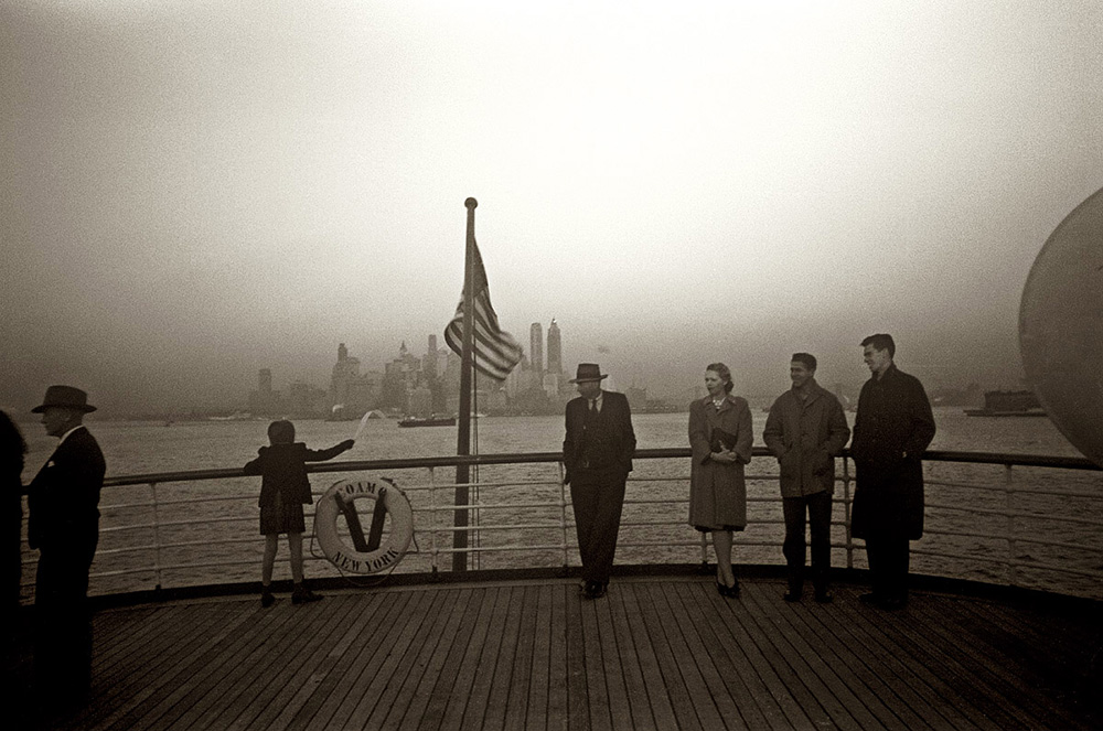 Пассажиры стоят на корме отходящего от Нью-Йорка корабля.